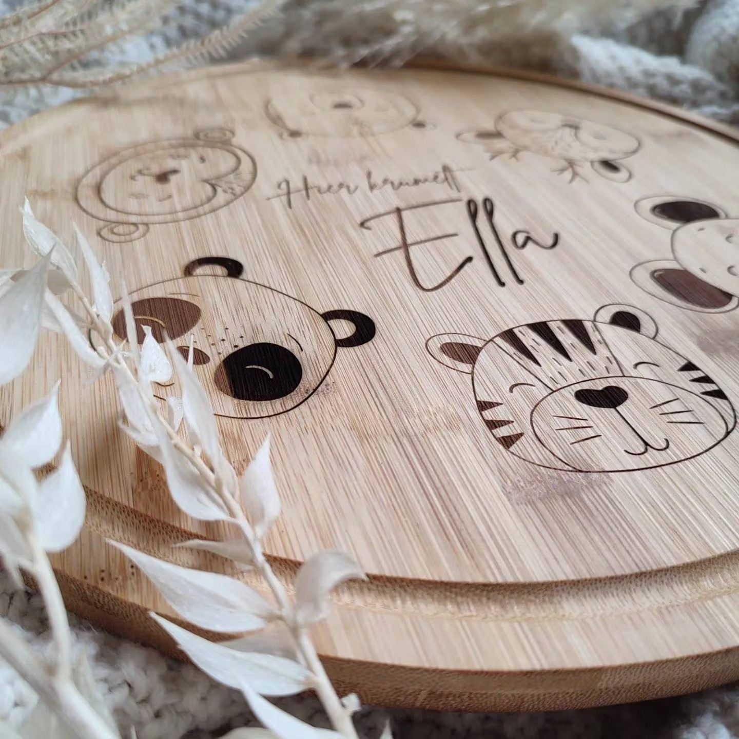 Nahaufname eines runde Schneidebretts mit personalisiertem Namen und süßen Tiermotiven